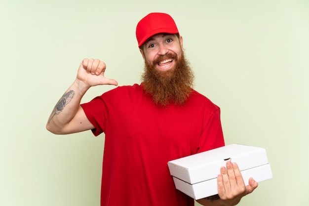 Fattorino con la barba lunga sopra la parete verde isolata fiera e soddisfatta di sé