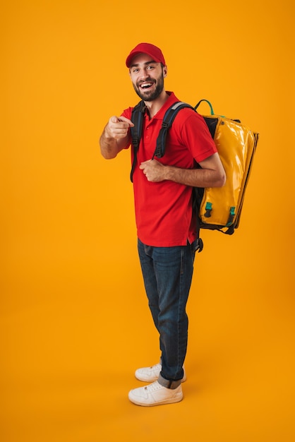 fattorino positivo in uniforme rossa che porta zaino con cibo da asporto isolato su giallo