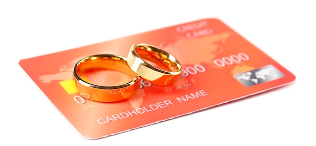 Fedi nuziali dorate e carta di credito isolate su bianco Concetto di matrimonio di convenienza