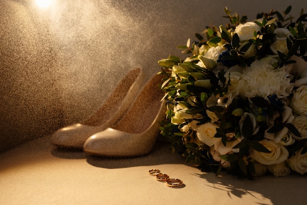 Fedi nuziali e anelli di fidanzamento con bouquet da sposa, scarpe da sposa