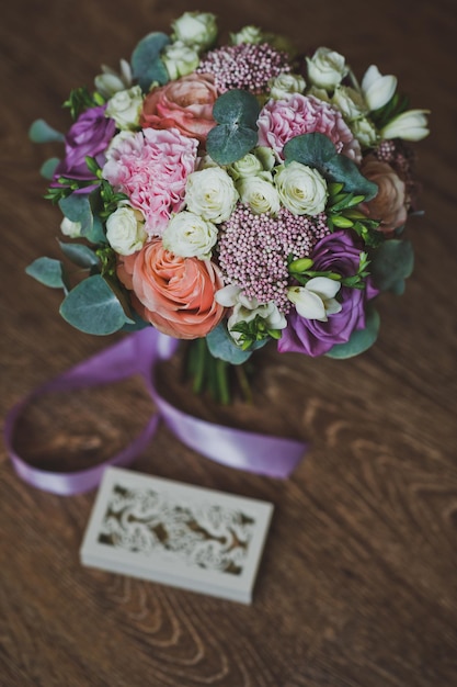 Fedi nuziali in una bella scatola intagliata e un bouquet colorato 2232