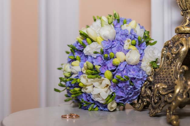 fedi nuziali si trovano e bellissimo bouquet come accessori da sposa. Due anelli d'oro e fiori da sposa. Biglietto di auguri, invito, fiori colorati bianco e blu fresia e ortensia. Copia spazio