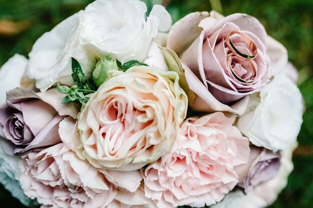 Fedi nuziali sposa e sposo sullo sfondo bouquet da sposa con delicati fiori pastello