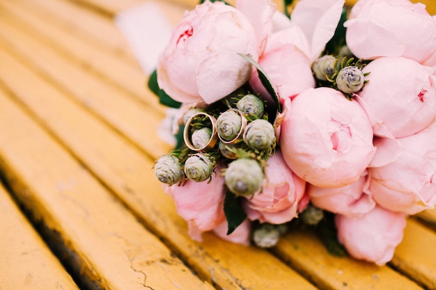 Fedi nuziali su un bouquet di peonie