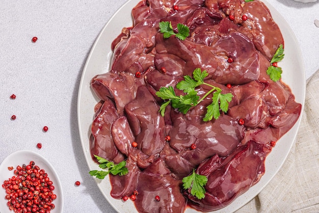 Fegato di pollo crudo su sfondo di pietra Ingredienti freschi pronti per cucinare prezzemolo pepe rosso Vista dall'alto alla moda, dura, chiara, scura, piatta