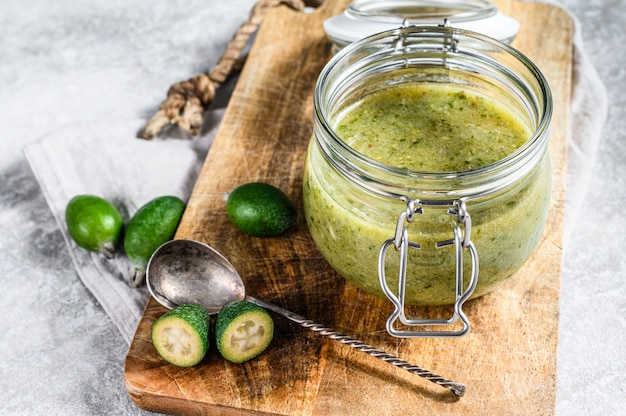 Feijoa verde a terra con zucchero su un tagliere di legno in un barattolo di vetro.