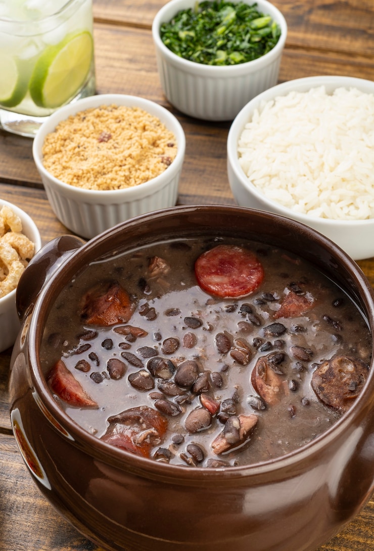 Foto feijoada brasiliana tradizionale con riso, cavolo riccio, farina di manioca e caipirinha.