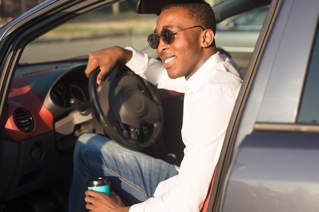 Felice afroamericano alla guida di un'auto, in estate