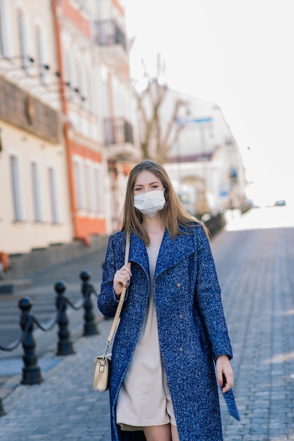 Felice allegra giovane donna in maschera medica facciale mentre si trova in strada in città.