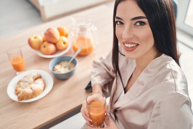 Felice allegra signora seduta in cucina a casa la mattina e sorridente