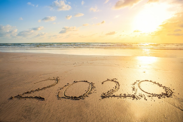 Felice anno nuovo 2020 testo sulla bellissima spiaggia del mare con onda alba del primo mattino sopra l'orizzonte