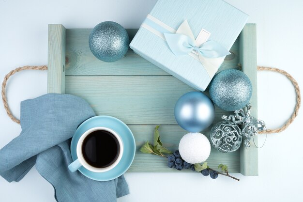 Felice anno nuovo 2021, composizione festosa con una tazza di caffè, scatola regalo, palloncini natalizi e un vassoio in un morbido colore blu