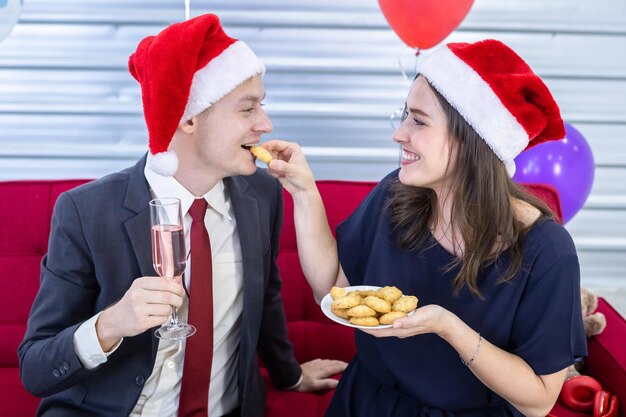 Felice anno nuovo 2022 concetto, coppia felice Tenere un bicchiere di champagne e mangiare i biscotti nella festa di Natale e Capodanno Dopo aver terminato il lavoro aziendale