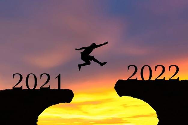 Felice Anno Nuovo 2022 Gli uomini saltano sopra le montagne e il sole della siluetta