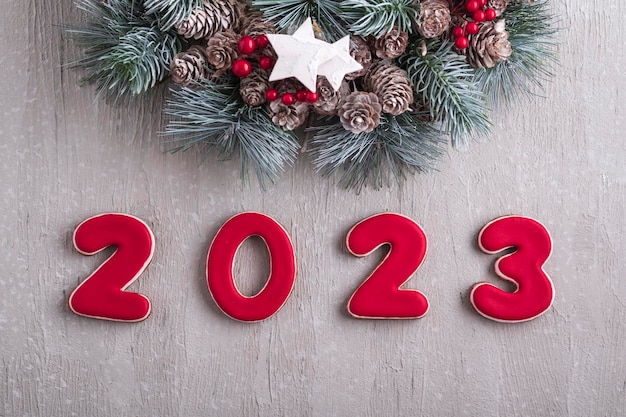 Felice anno nuovo 2023 Biscotti di pane allo zenzero rosso e ghirlanda di Natale Parete grigio chiaro sullo sfondo