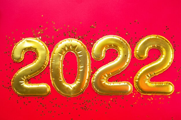 Felice Anno Nuovo - numeri dorati 2022 su sfondo rosso con paillettes, stelle, glitter. Saluti, cartolina. Calendario, copertina.