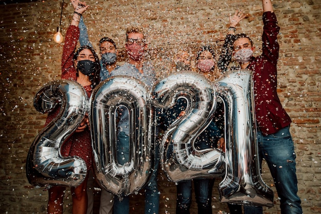 Felice anno nuovo! Un gruppo di giovani che indossano una maschera per il viso per celebrare il 2021