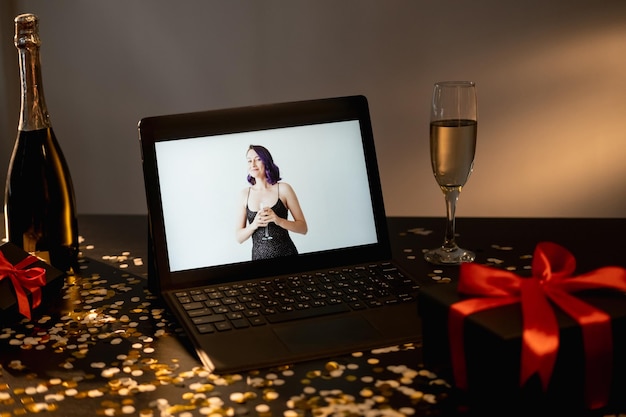 Felice anno nuovo video saluto vacanza celebrazione donna festiva che si congratula per il regalo nero del computer portatile