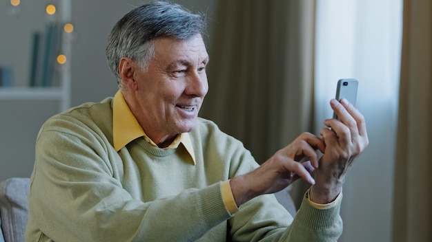 Felice anziano anziano uomo adulto che tiene il telefono effettua videochiamata sorridente nonno guardando