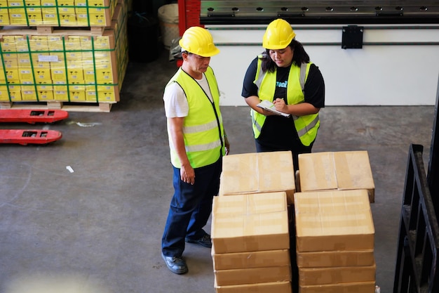 Felice asiatica lavoratrice obesa e senior manager magazzino in giubbotto di sicurezza e casco hardhat