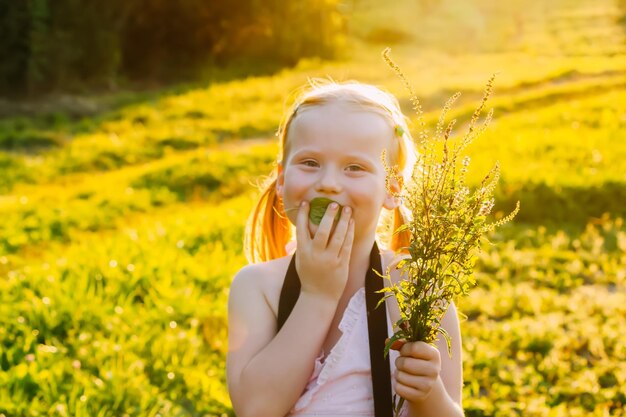 Felice bambina bionda con fiori di campo