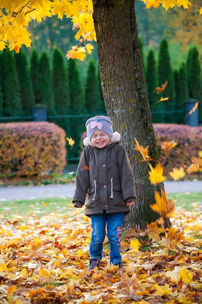 Felice bambina di 3-4 anni che gioca con le foglie nel parco autunnale. Caduta delle foglie d'autunno.