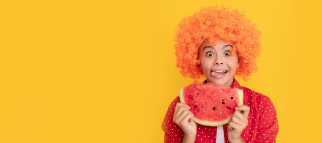 Felice bambino affamato in fantasia capelli arancioni parrucca tenere fresca fetta di melone d'acqua matura fame di frutta Ritratto di ragazza estiva con poster orizzontale di anguria Intestazione banner con spazio di copia