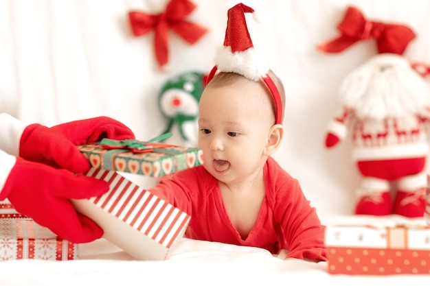 Felice bambino con cappello da Babbo Natale rosso e scatole regalo di Natale di capodanno Mani in guanti Buon Natale