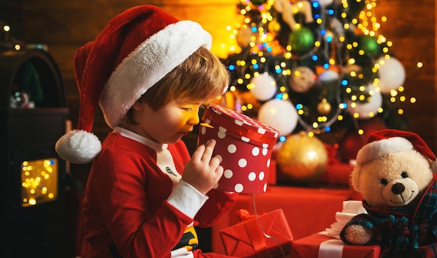 Felice bambino eccitato sta aprendo una confezione regalo ragazzino felice e sorridente con confezione regalo di natale sorpreso c