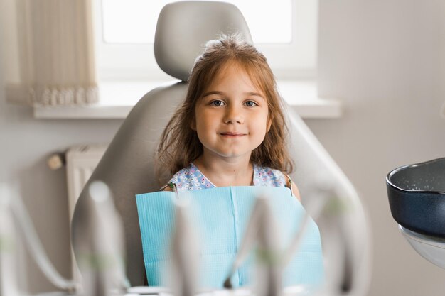 Felice bambino paziente di odontoiatria Trattamento dei denti Ragazza attraente del bambino seduto in studio dentistico e sorridente Bambino al dentista in visita