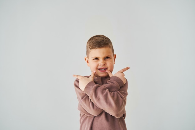 Felice bel bambino ragazzo sorridente e punta le dita verso l'alto per scegliere Pubblicità aziendale per negozi e negozi per bambini