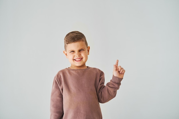 Felice bel bambino ragazzo sorridente e puntando il dito sul lato destro Pubblicità aziendale per negozi e negozi per bambini