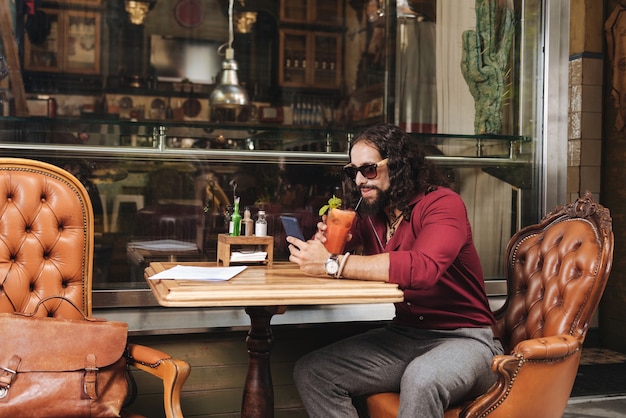 Felice bel uomo che indossa occhiali da sole pur essendo nel caffè