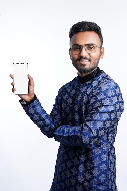 Felice bell'uomo indiano che indossa abiti tradizionali tenendo o utilizzando il telefono cellulare per celebrare il festival di diwali e dare espressione