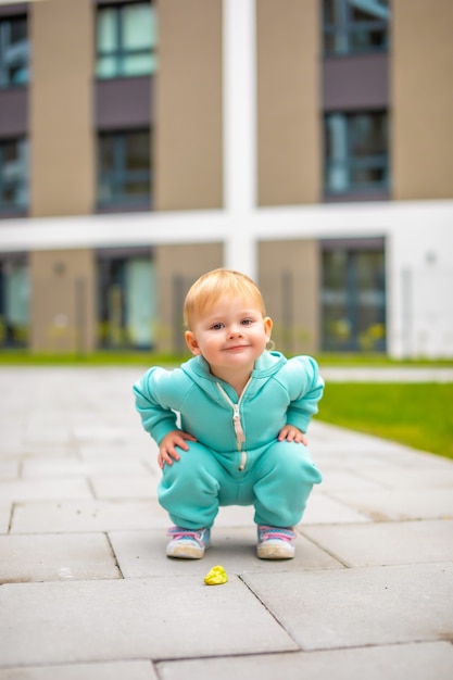 Felice bella bambina in buona salute in tuta blu che si diverte in città ragazzo attivo in una fredda giornata all'aperto