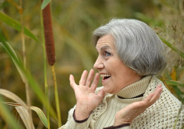 Felice bella donna anziana nel parco autunnale