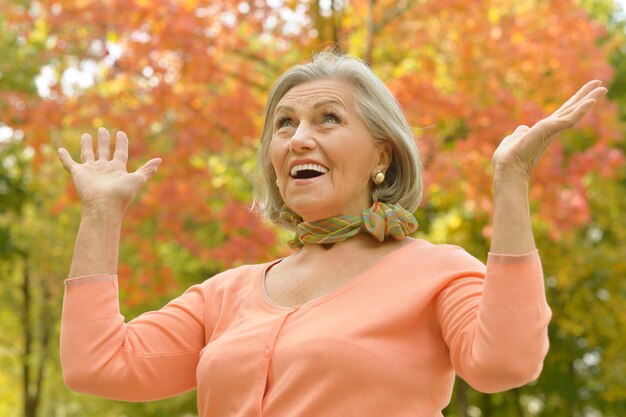 Felice bella donna anziana nel parco autunnale