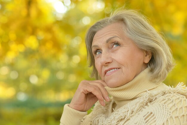 Felice bella donna anziana nel parco autunnale