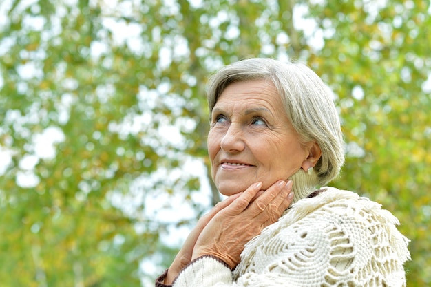 Felice bella donna anziana nel parco autunnale