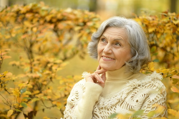 Felice bella donna anziana nel parco autunnale