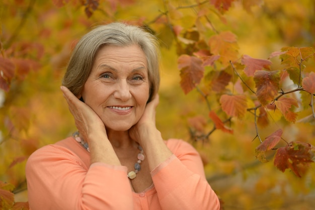 Felice bella donna anziana nel parco autunnale