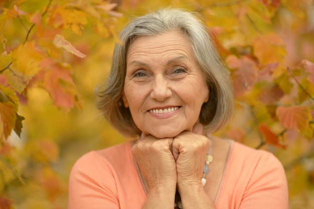 Felice bella donna anziana nel parco autunnale