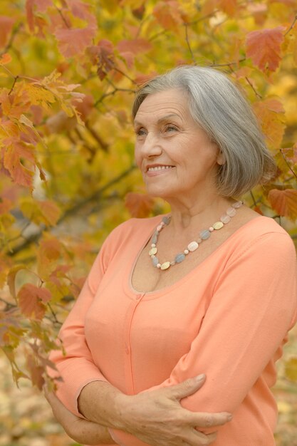 Felice bella donna anziana nel parco autunnale