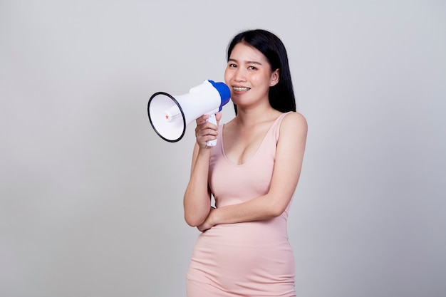 Felice bella donna asiatica parlando su magaphone isolato su sfondo grigio chiaro con copia spazio