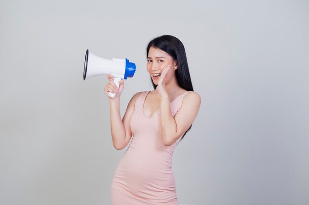 Felice bella donna asiatica parlando su magaphone isolato su sfondo grigio chiaro con copia spazio