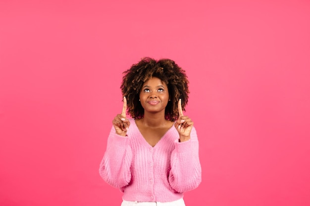 Felice bella donna riccia afroamericana millenaria in uno spettacolo casual dita su uno spazio vuoto