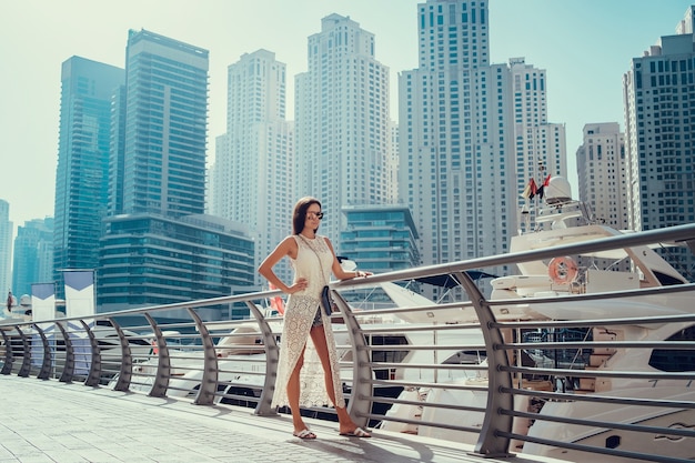 Felice bella donna turistica irriconoscibile in abito bianco estivo alla moda godendo a Dubai