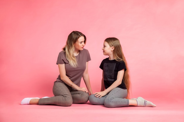 Felice bella madre e sua figlia in abiti casual su sfondo rosa. Concetto di trascorrere del tempo insieme ai bambini e alle belle relazioni familiari. Copia spazio per il sito