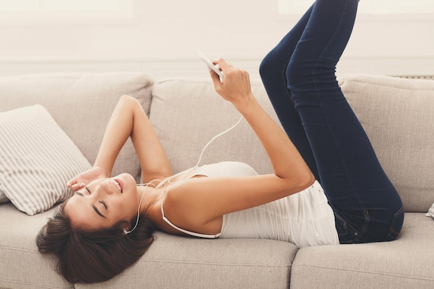 Felice bella ragazza che ascolta la playlist sul cellulare, godendosi la musica con gli occhi chiusi
