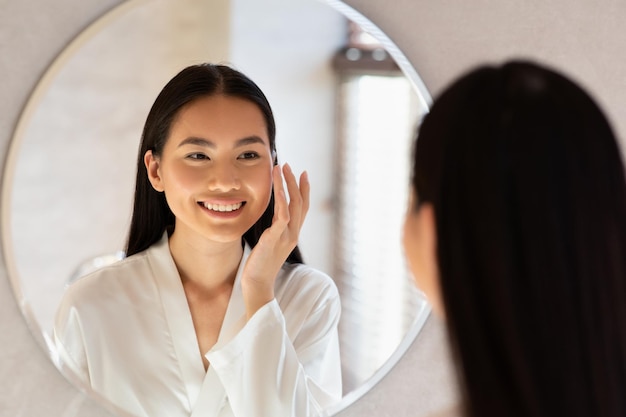 Felice bella signora coreana con crema viso idratante